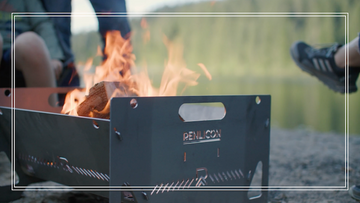 Close up image of Renlicon Portable Fire Pit with flames and a lake in the background.
